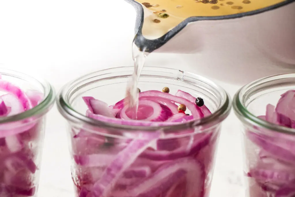 Pouring brine over red onions.