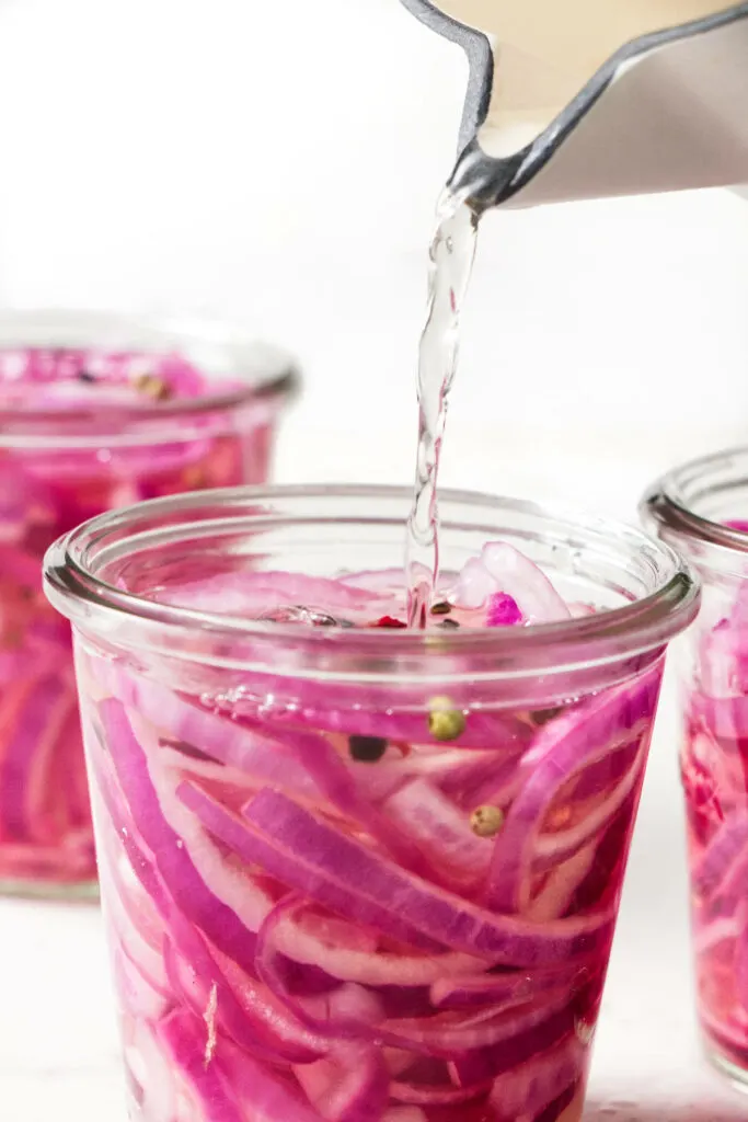 Pouring brine over red onions.