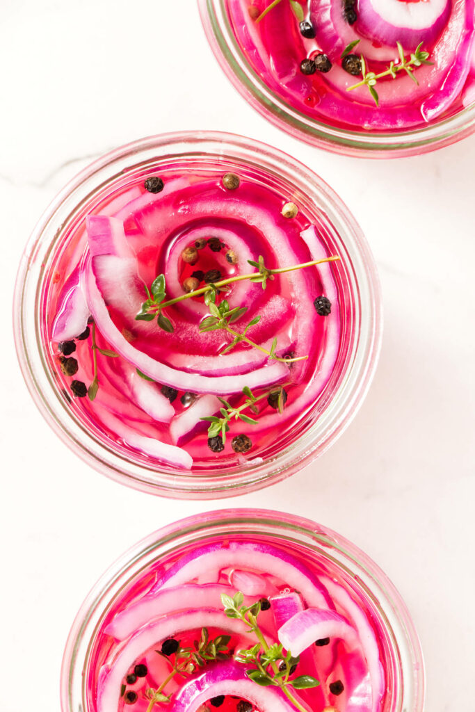 Three jars filled with pickled onions.