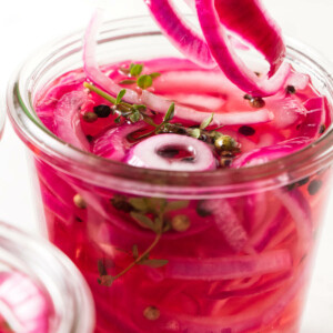 A fork scooping out some pickled onions from a jar.