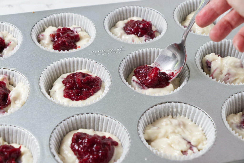 Adding jam to the center of muffins.