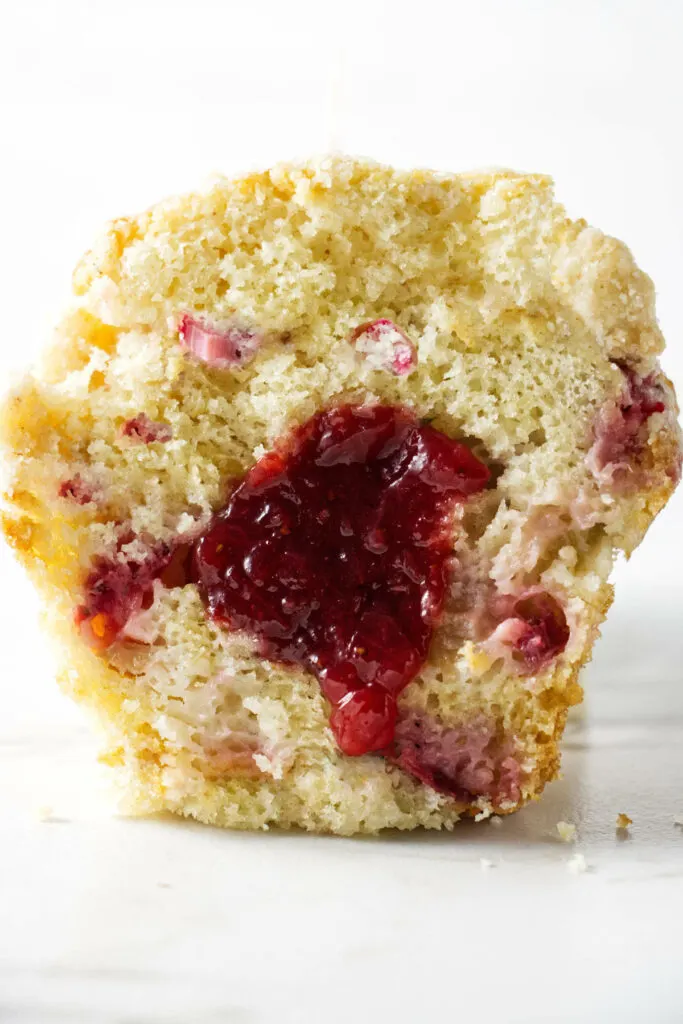 A muffin sliced in half showing a jam filling.