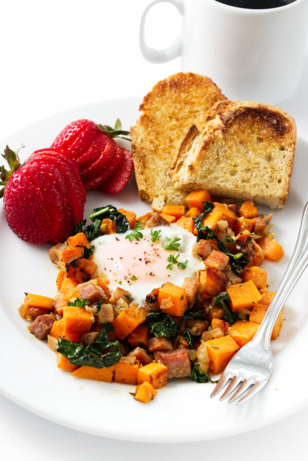 Diced breakfast sweet potatoes on a plate with toast and strawberries.