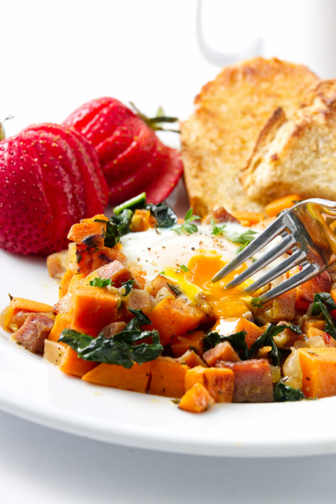 A fork scooping up a bite of breakfast sweet potato hash.