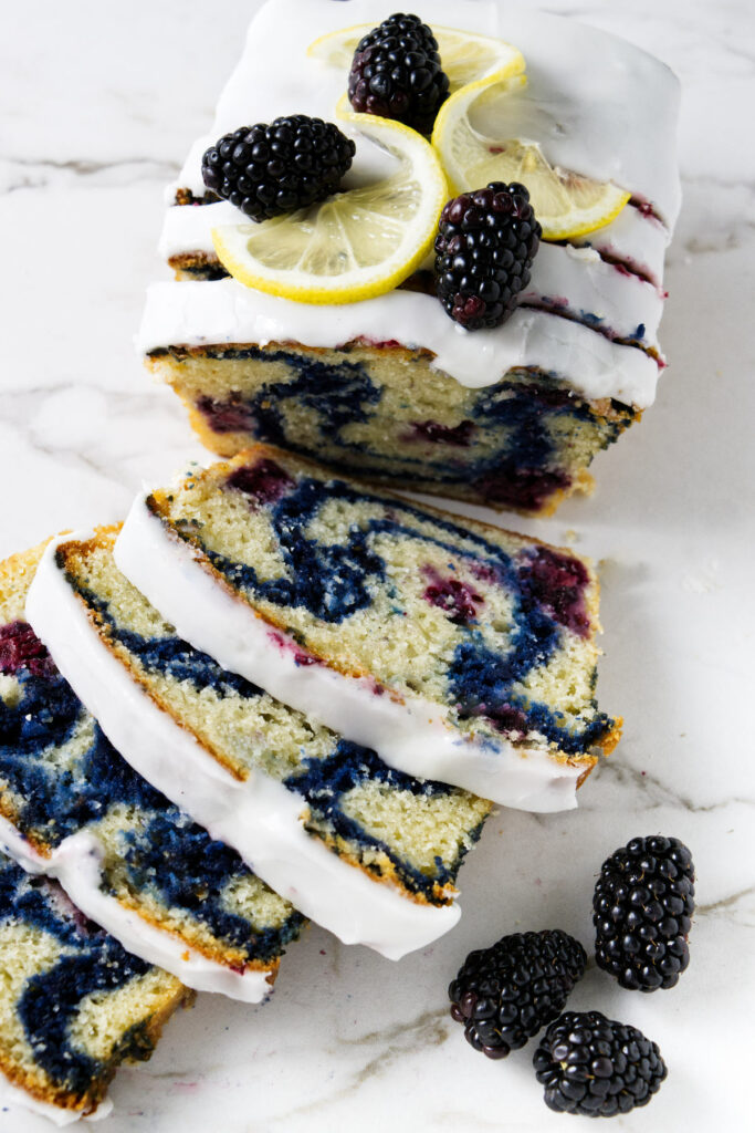 A loaf of blackberry bread with lemon slices and blackberries on top.
