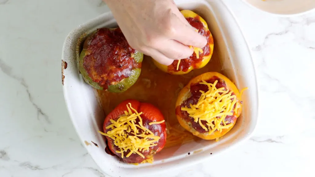 Inserting cheese on top of stuffed bell peppers.  Einkorn Berries and Beef Stuffed Peppers chicken stuffed peppers 112 1024x576