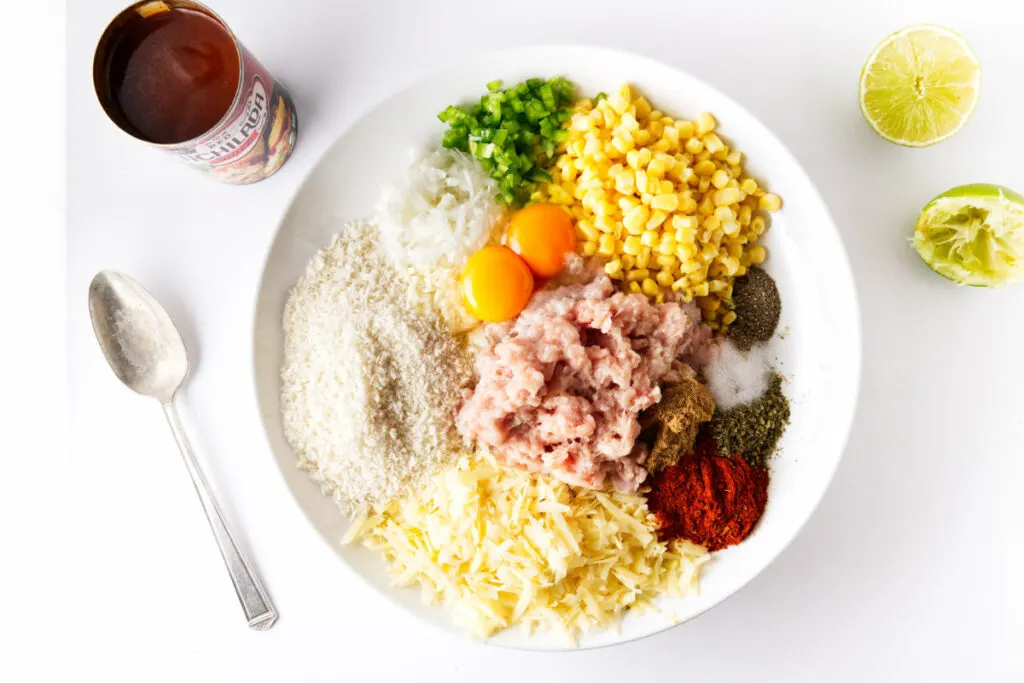 A bowl filled with ground chicken, rice, cheese, spices, eggs, onions, jalapeno pepper, and enchilada sauce.