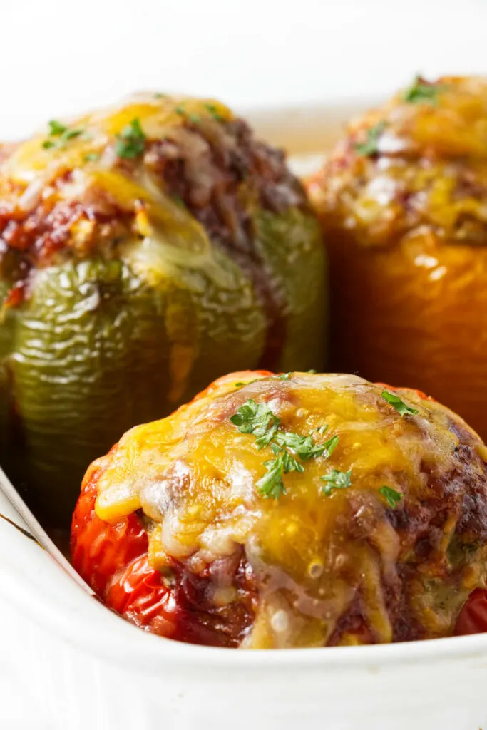 Stuffed bell peppers in a baking dish with melted cheese on top.