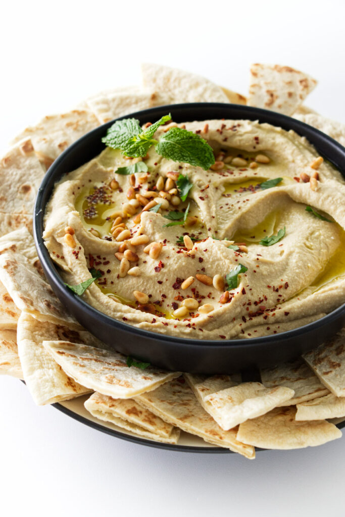 A dish of hummus dip surrounded by pita bread wedges.