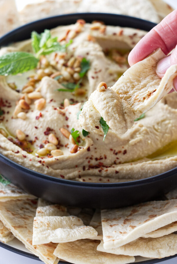 Dipping pita bread into a bowl of hummus.