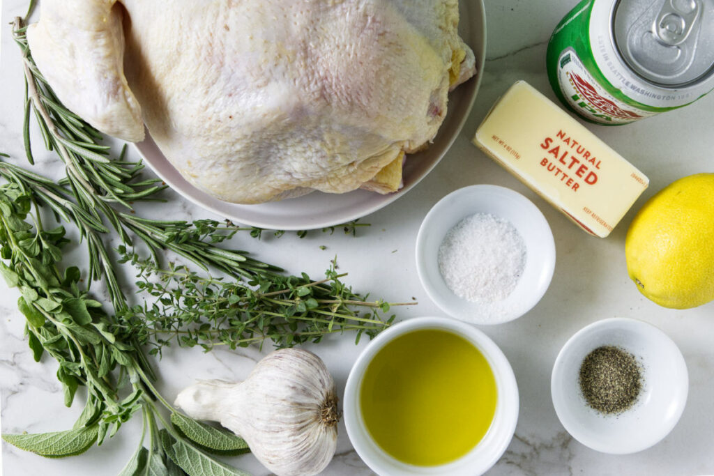 A whole chicken, fresh herbs, garlic, olive oil, butter, salt, pepper, lemon, and a can of beer.