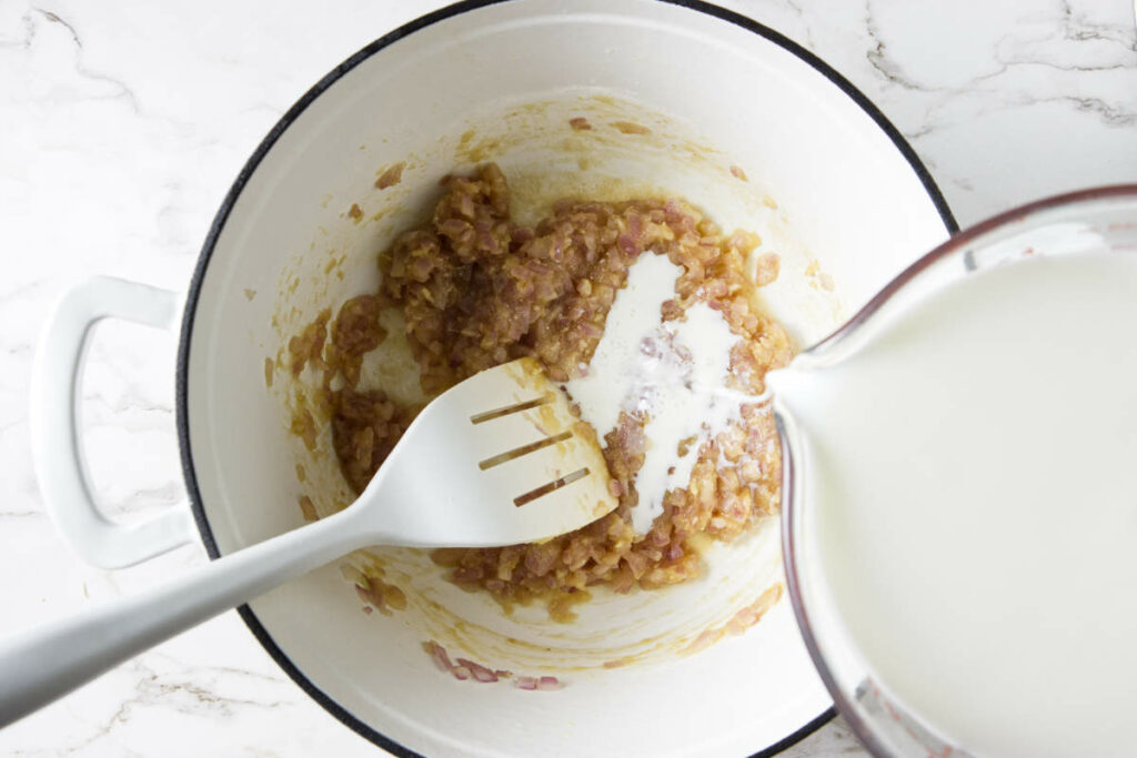 Pouring milk in a roux.