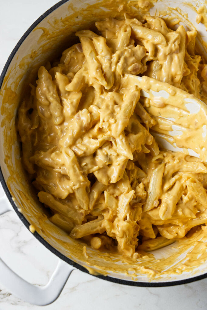 Stirring cheesy Buffalo sauce into pasta.