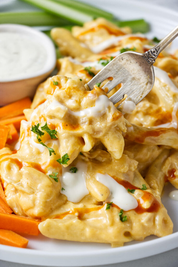 A fork taking a bite of Buffalo chicken pasta.