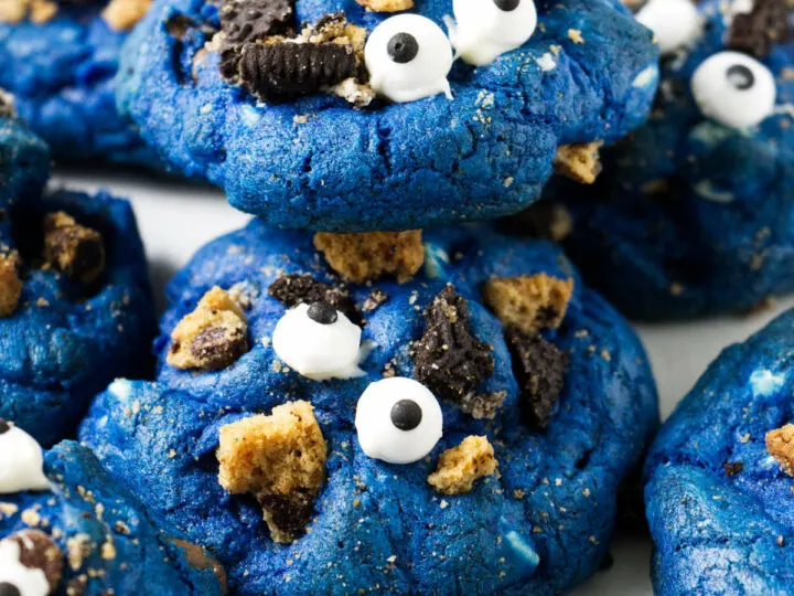 Several blue cookies with candy eyeballs on top.