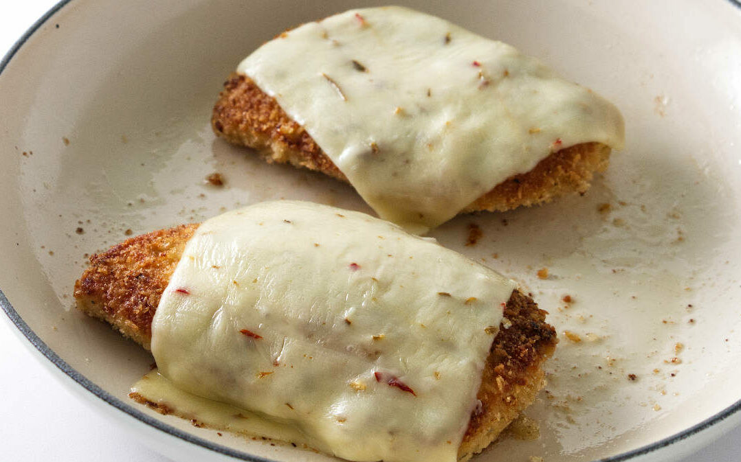 preparing  spicy crispy chicken topped with cheese