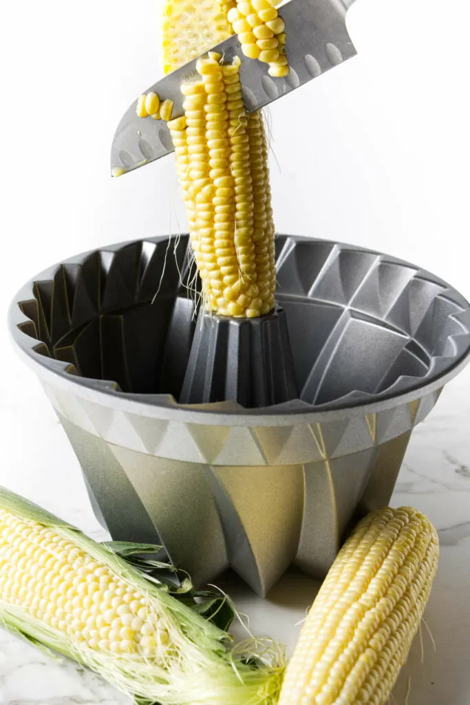 Slicing kernels corn off a corn cob.