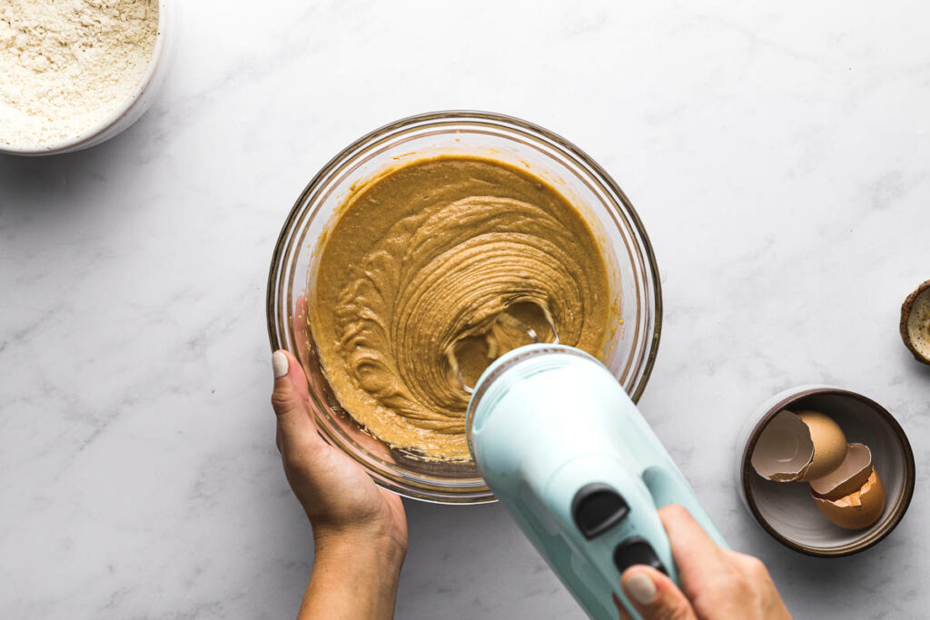 Using a mixer to blend peanut butter, eggs, and sugar.