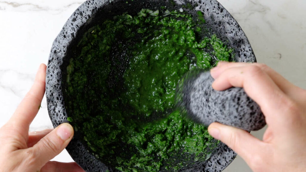 Grinding onions and jalapenos into a paste.