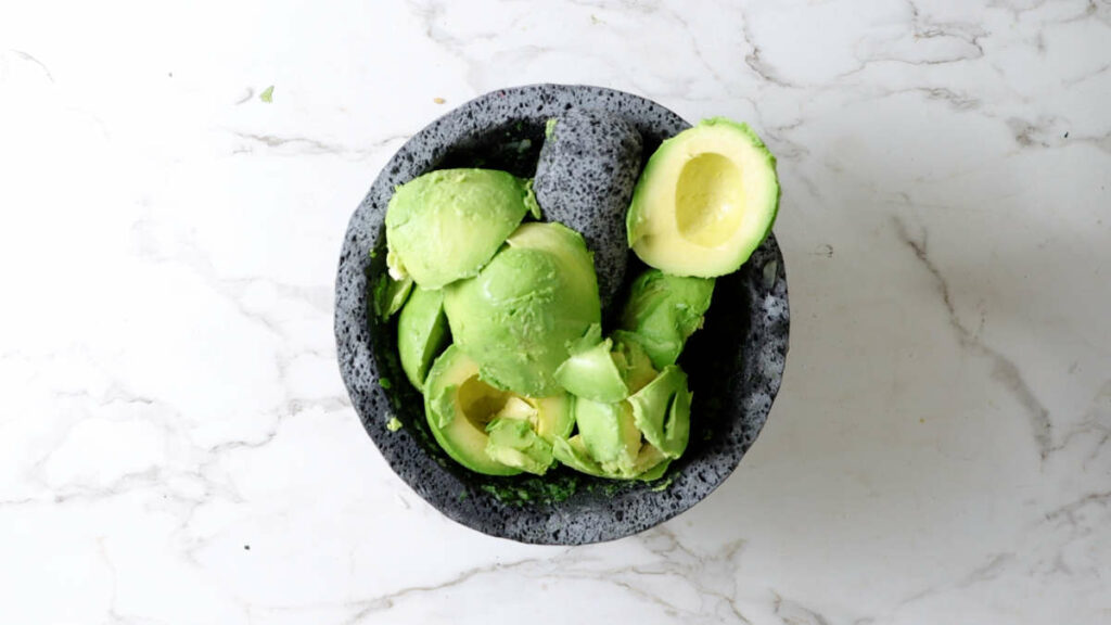 Sliced avocados in a molcajete.