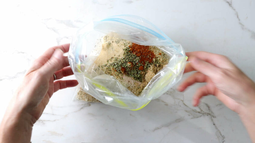 Combining bread crumbs and seasoning in a resealable plastic bag.