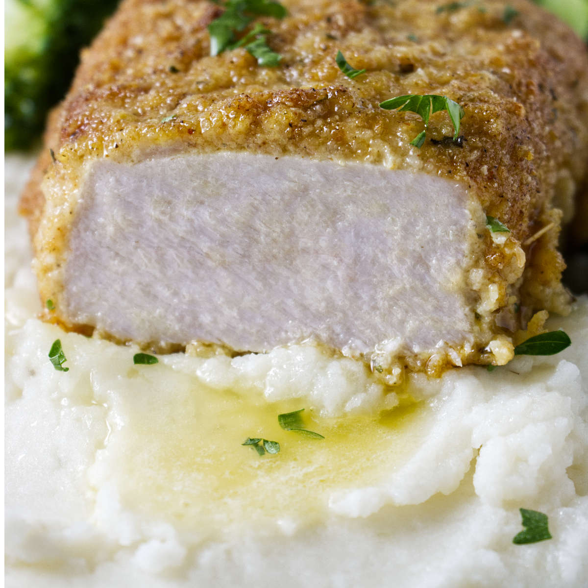 A breaded pork chop in a bed of mashed potatoes.