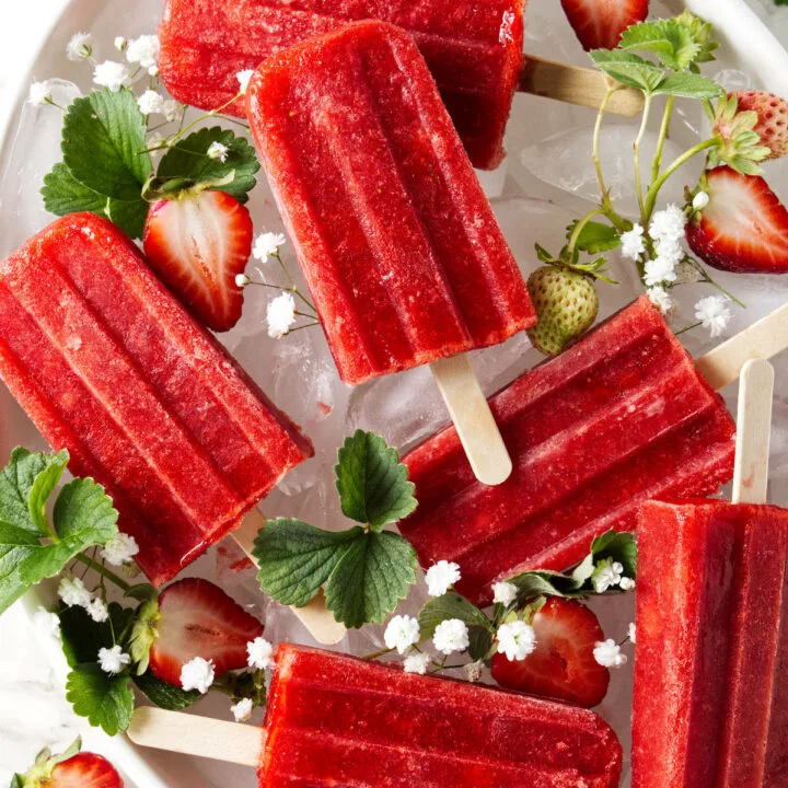 Homemade strawberry popsicles in a bowl of ice.