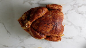 Adding a dry rub to a chicken.