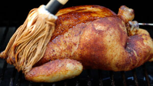 Brushing a chicken with a mop sauce.