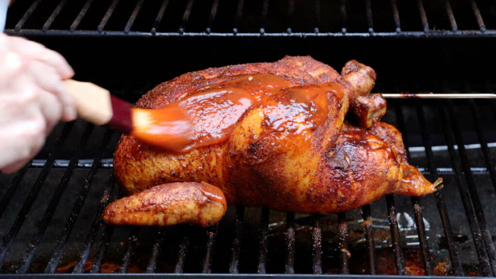 Adding barbecue sauce to a whole chicken.