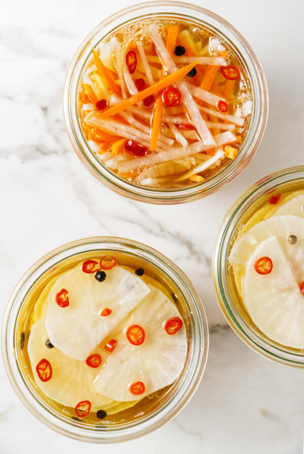 Three jars filled with pickled daikons and carrots.