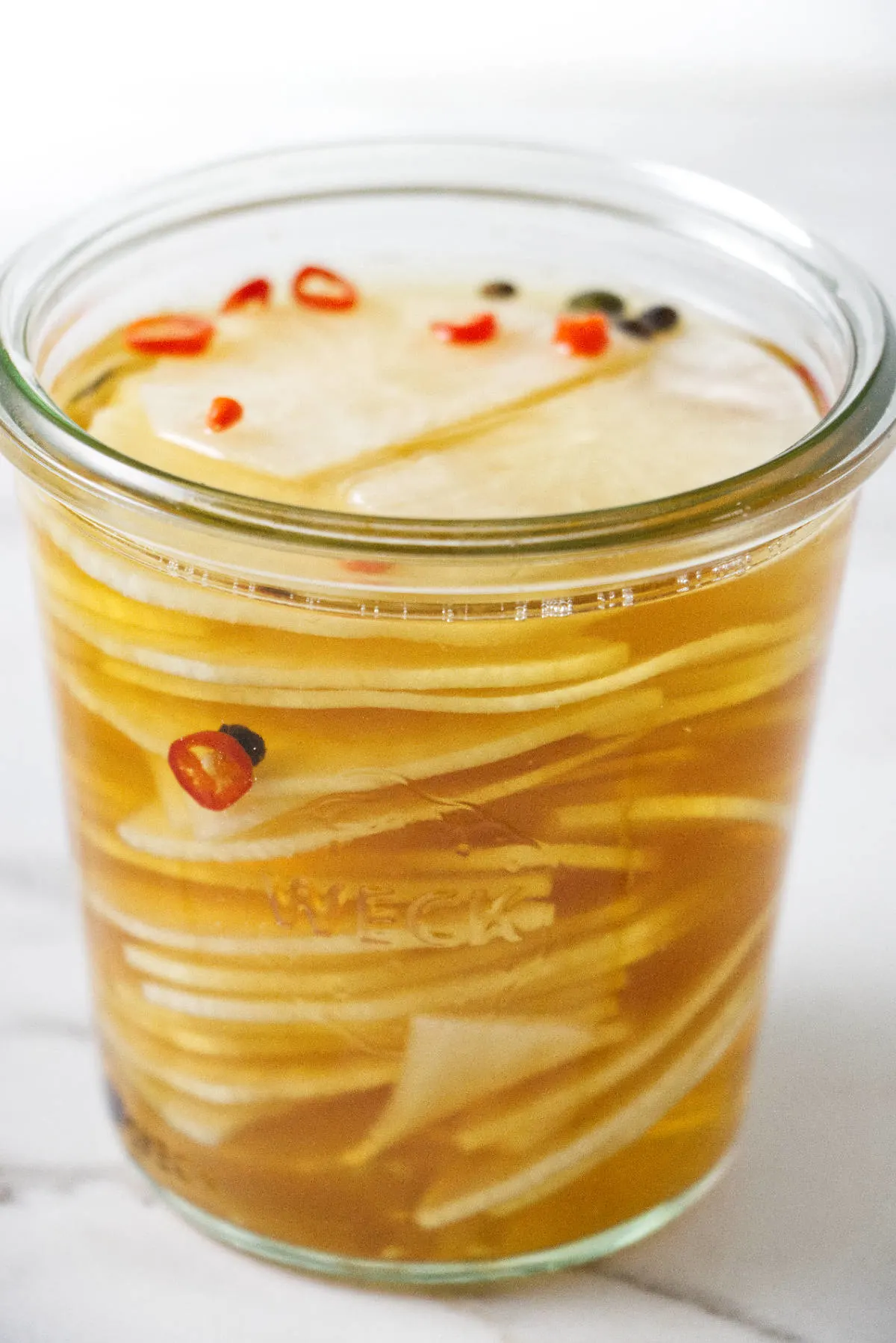 Sliced daikons in a jar with pickling brine.