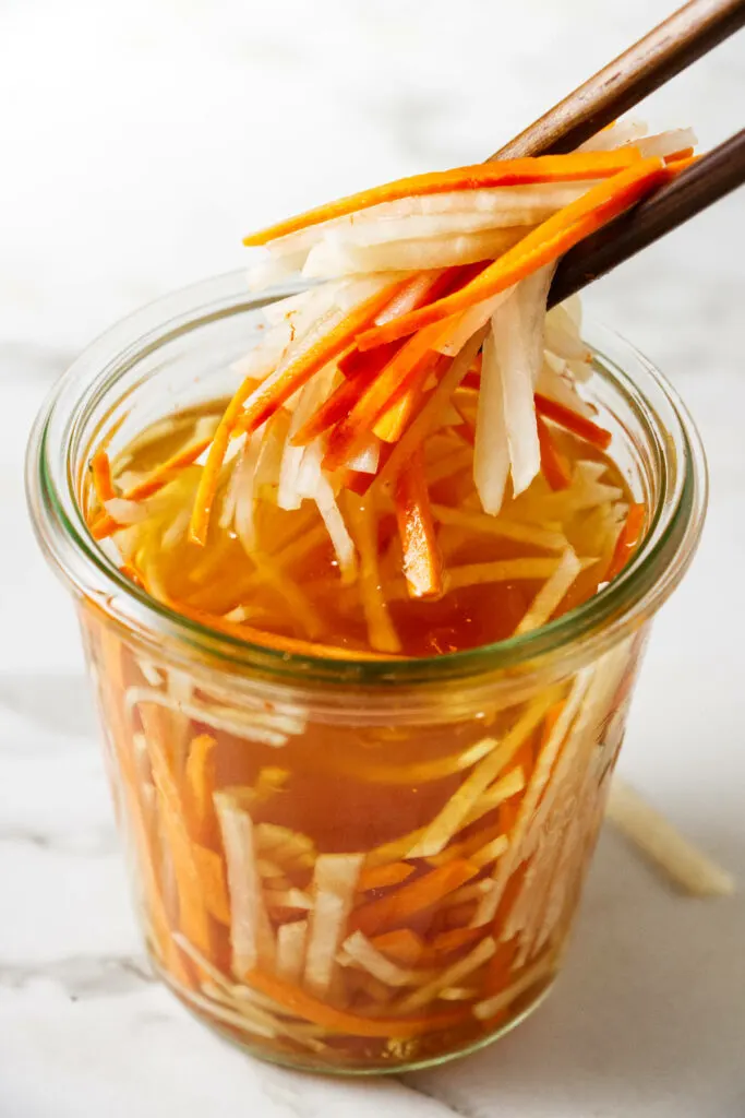 Julienned daikons and carrots in a jar.