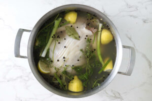 A whole chicken in a pot with brine solution.