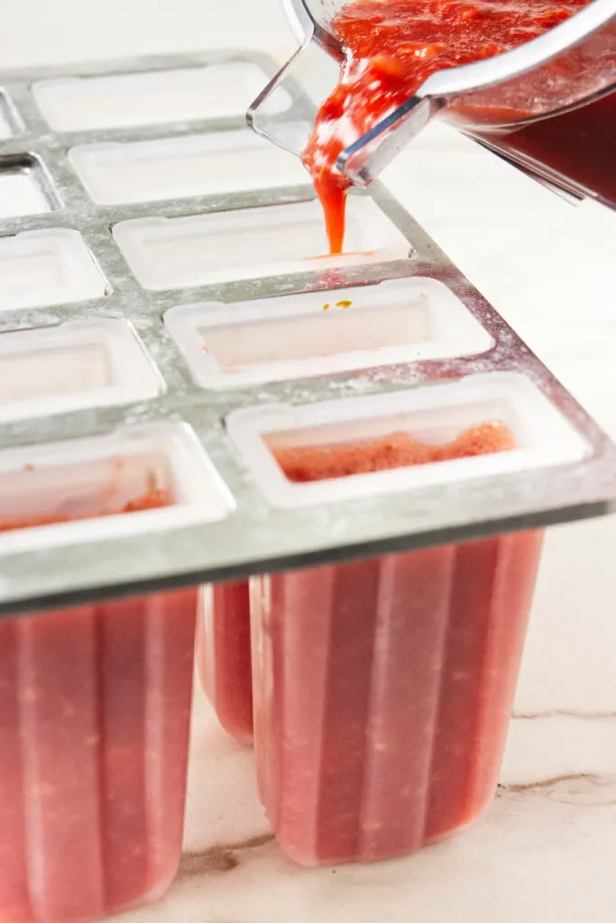 Pouring strawberry puree into popsicle molds.