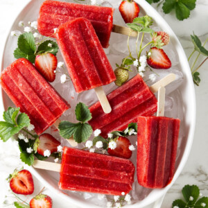 Strawberry popsicles in a dish on top of ice.