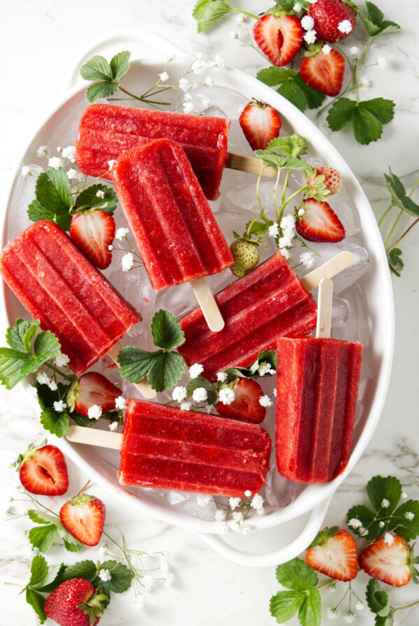 Strawberry popsicles in a dish on top of ice.