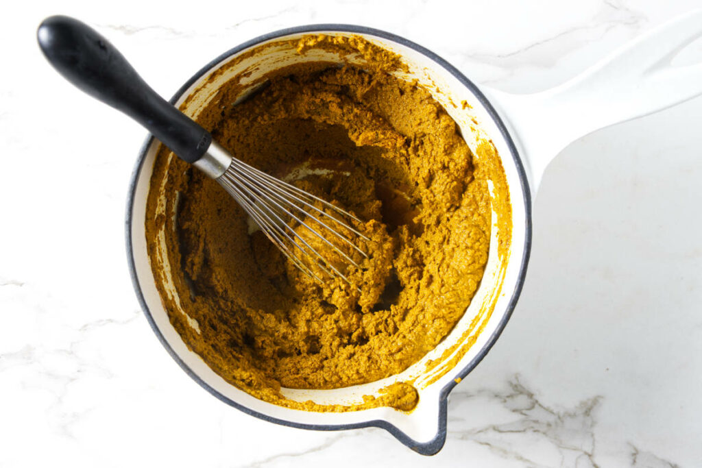 Cooking turmeric and spices into a thick golden paste.