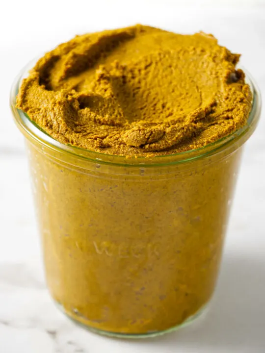 A glass jar filled with turmeric paste.