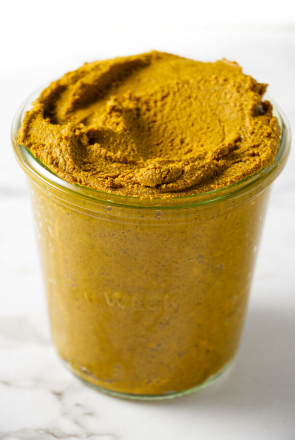 A glass jar filled with turmeric paste.