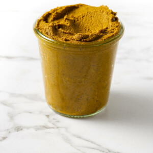 A glass jar filled with turmeric paste.