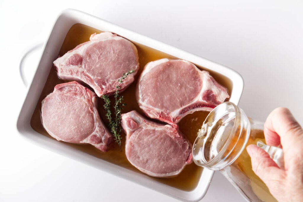 Dish with pork chops and a brine being poured into the dish