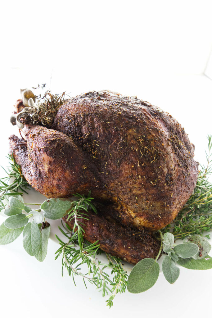 Roasted turkey on a plate garnished with fresh herbs.