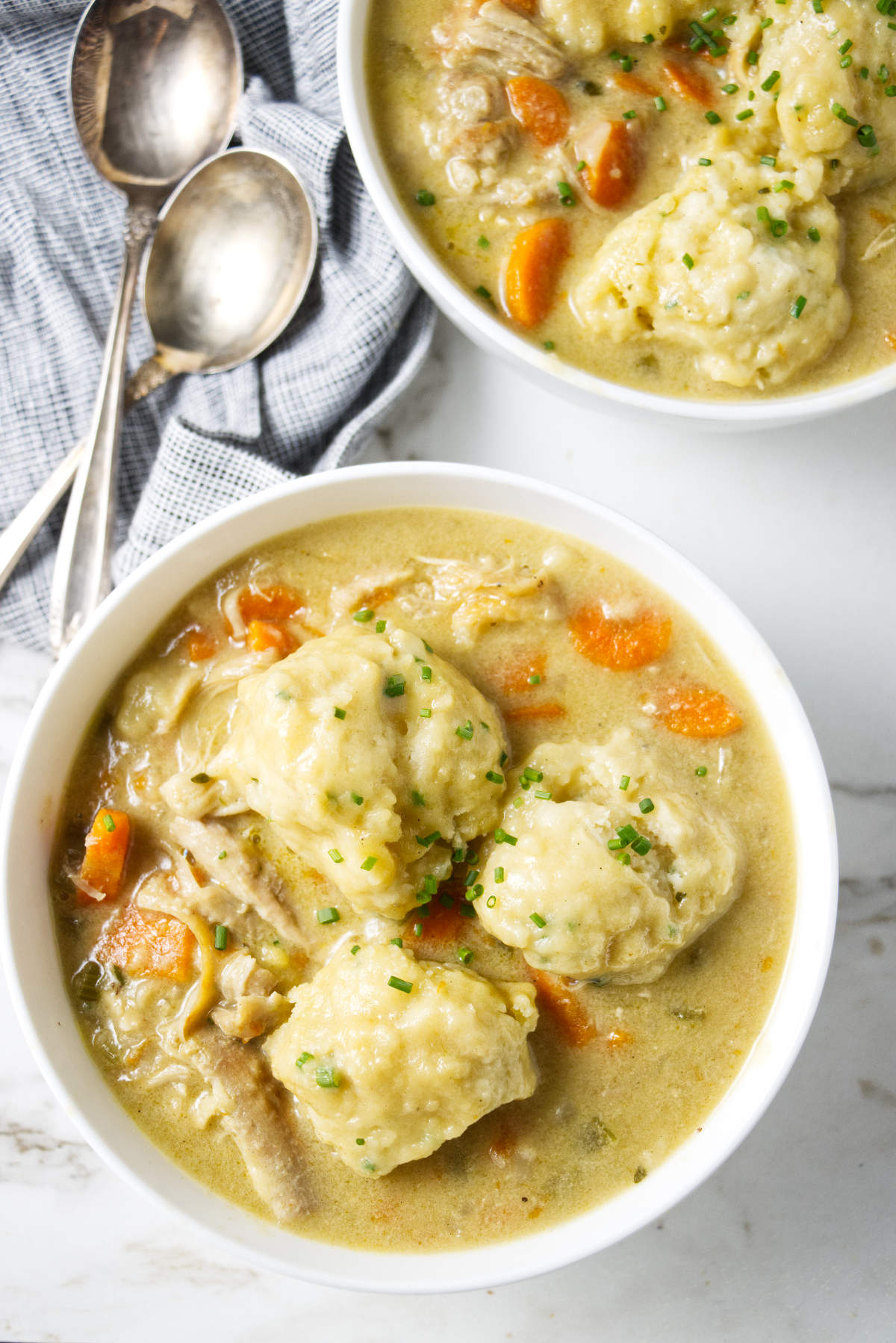 Three large dumplings in a bowl of creamy chicken soup.