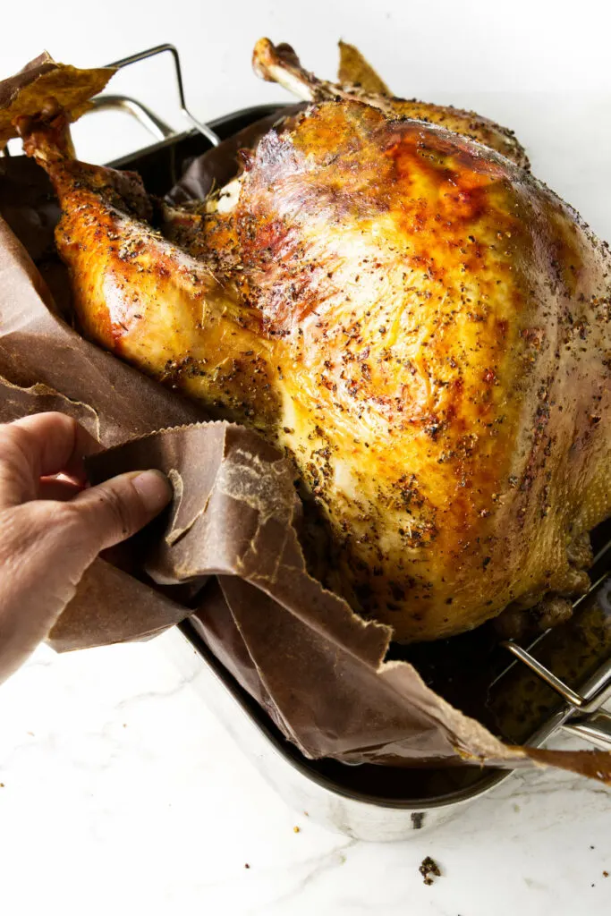 Removing a roasted turkey from a brown paper bag.