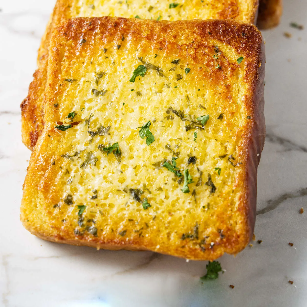 A thick slice of garlic bread made with Texas toast sandwich bread.