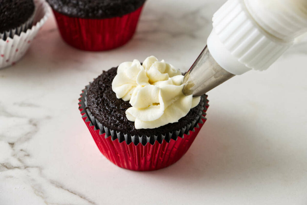 Piping buttercream on cupcakes.
