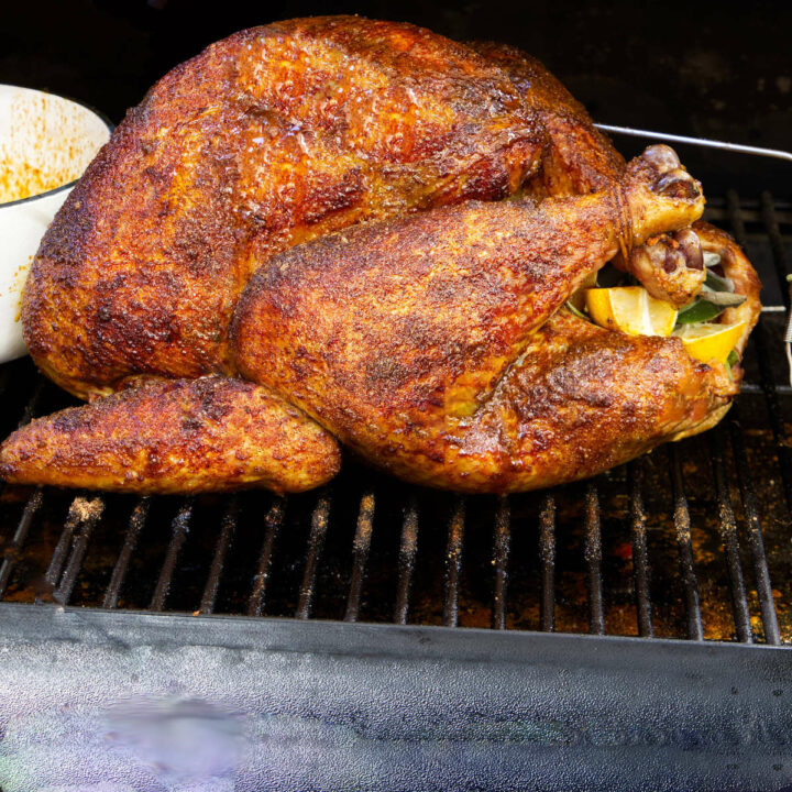 A smoked turkey cooking on grill grates.