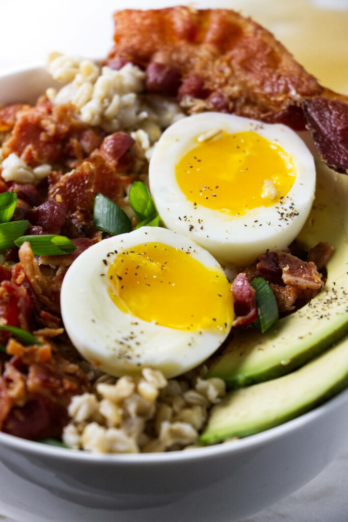 Breakfast oat groats topped with savory eggs, bacon, and avocados.