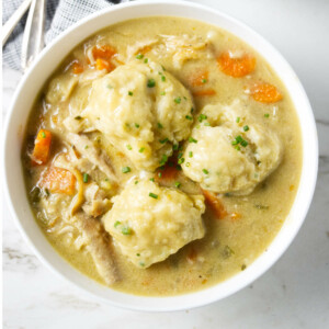 Three drop dumplings in in a bowl of chicken soup.